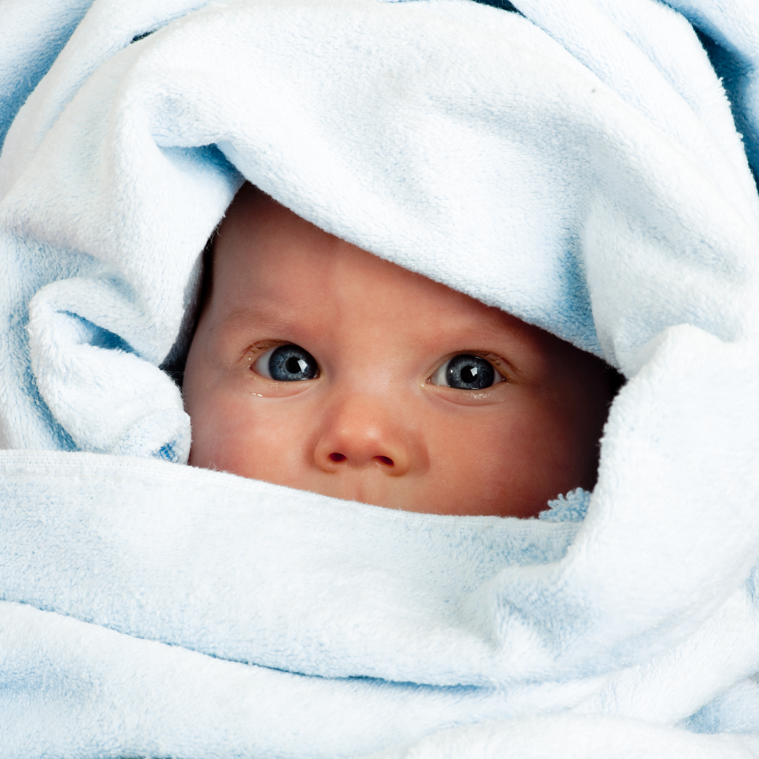 An infant wrapped in a cozy blue towel