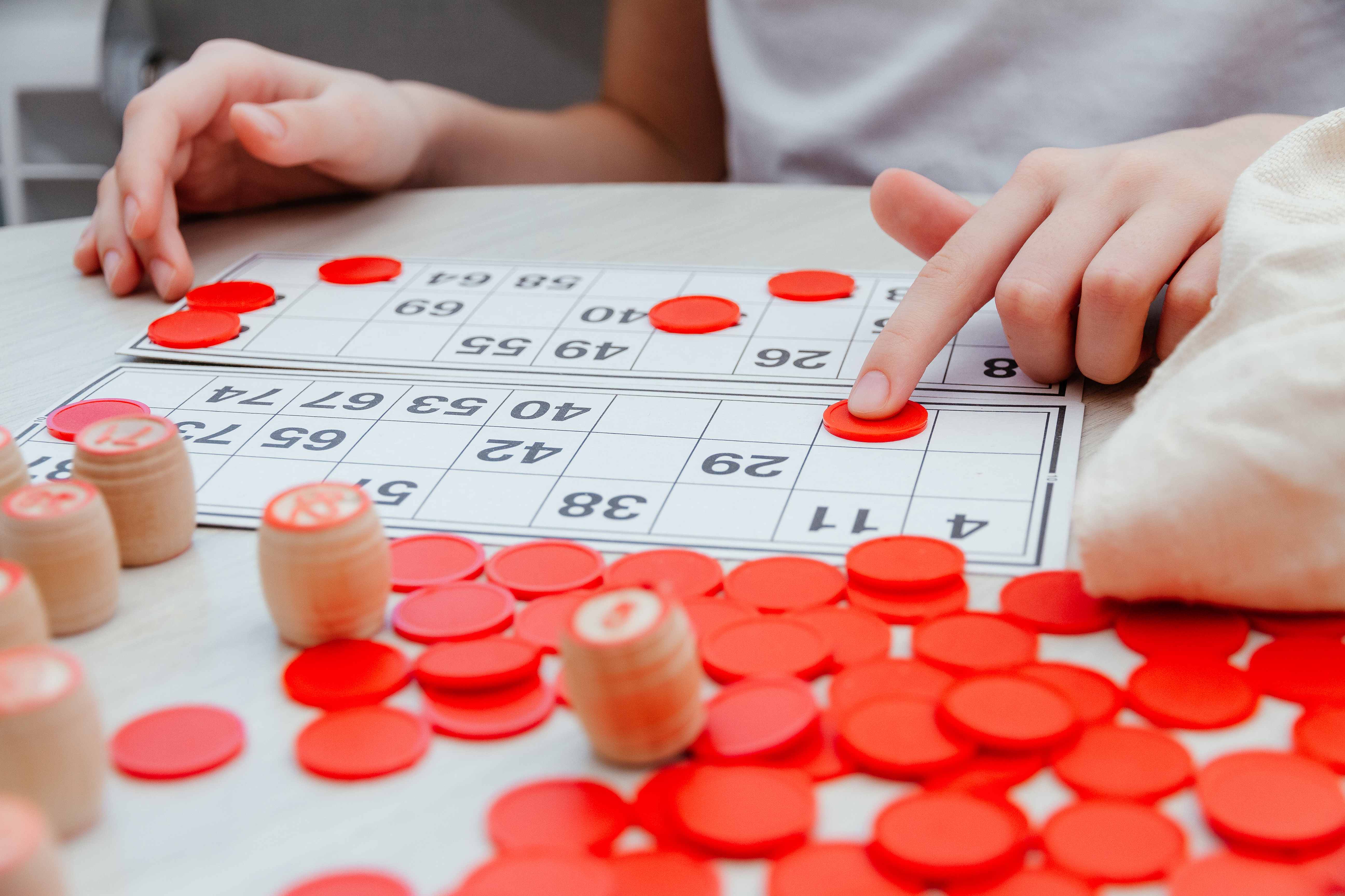 Hands placing red chips on a numbered bingo card