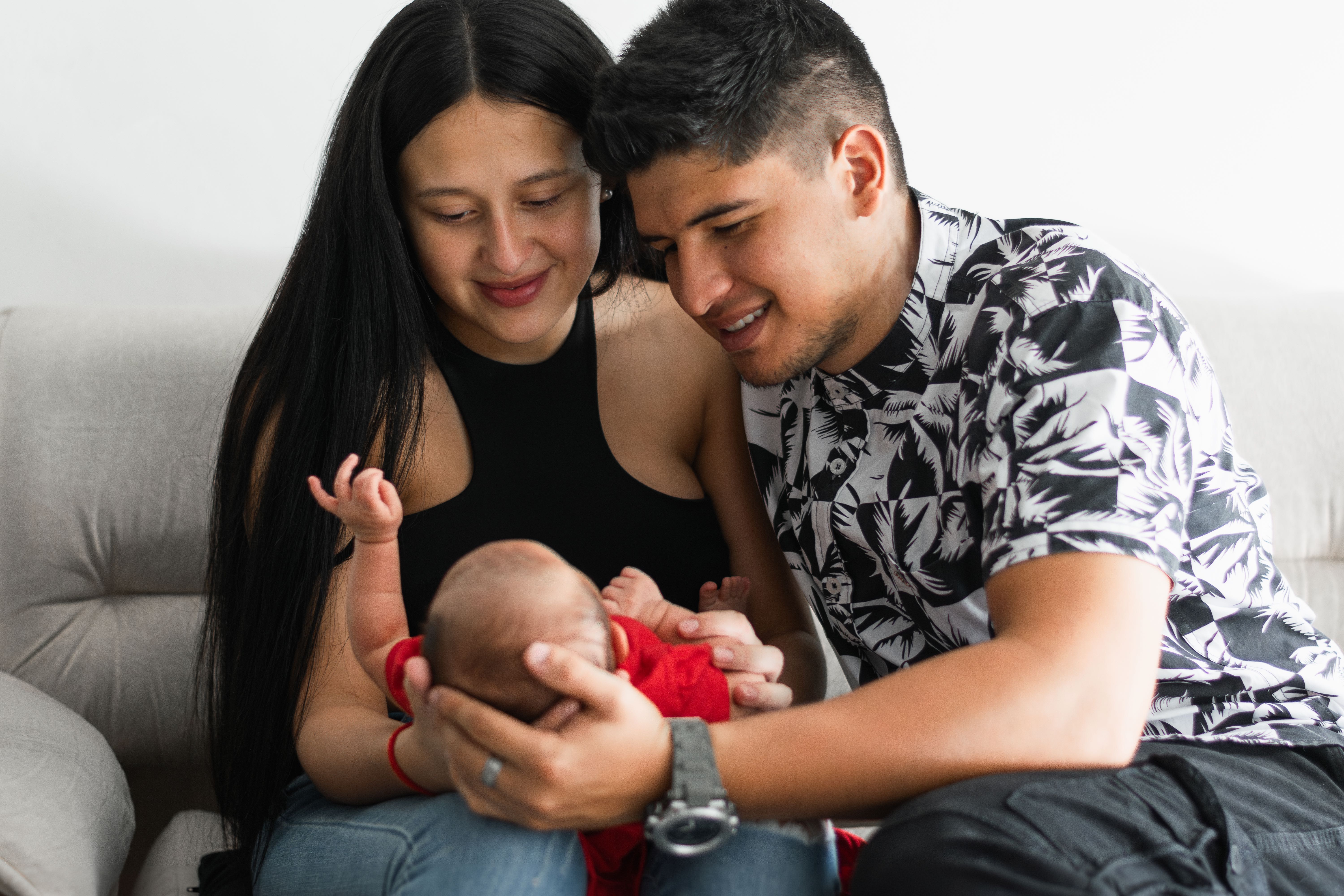 Smiling parents cradling their newborn baby together at home